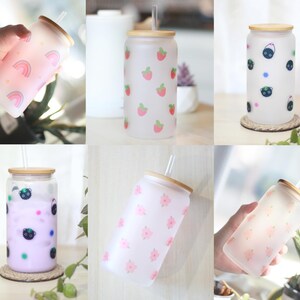May include: Six frosted glass tumblers with bamboo lids and straws. The tumblers feature different patterns: strawberries, black cats, rainbows, and flowers.