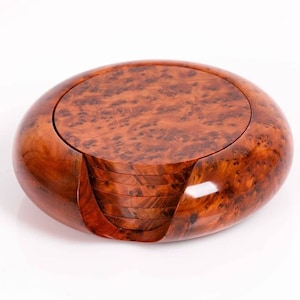 Peut inclure: Un ensemble de six sous-verres ronds en bois dans un support en bois brun. Les sous-verres sont en bois de couleur brun rougeâtre avec un motif de grain unique.