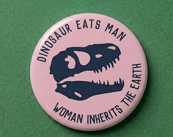 Plastic "Dinosaur Eats Man, Woman Inherits the Earth Pin" - Jurassic Park Dino Fashion Accessory