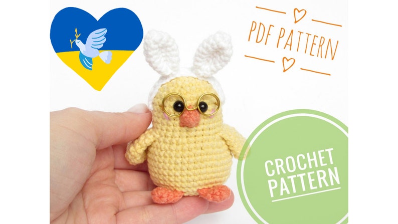 May include: Crochet pattern for a yellow chick wearing bunny ears and glasses. The pattern includes instructions for making the chick, ears, and glasses. The pattern is available as a PDF download. The image also includes a heart with the Ukrainian flag colors and a dove.
