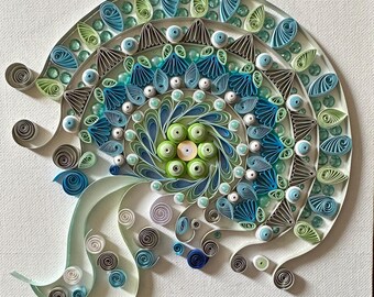 May include: A blue, green, and white paper quilling mandala with a swirling design. The mandala is framed and signed "Poudre".