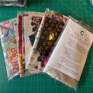 May include: A pack of fabric scraps for quilting and crafting. The pack includes a variety of prints and colours, including floral, geometric, and abstract designs. The pack also includes a description card with information about the fabric scraps.