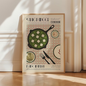 May include: A framed poster with a retro design featuring a dish of Saag Paneer, a popular Indian dish made with spinach and paneer cheese. The poster has a red and white checkered background with a green and white illustration of the dish. The text on the poster reads "Saag Paneer Delicious! 1998 Dish with cooked spinach and cubes of paneer cheese Made in India 490 Sai Road 401107 Mumbai."