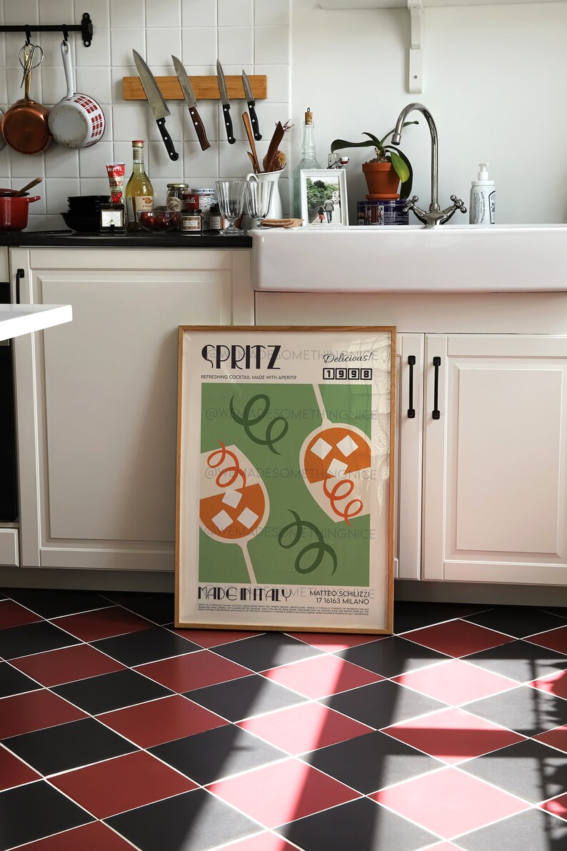 Pode incluir: Um p&ocirc;ster emoldurado com fundo verde e formas abstratas laranja e brancas. O p&ocirc;ster tem o texto "SPRITZ Delicious! Something Nice 1998" e "Made in Italy Matteo Schilizzi 17 16163 Milano".
