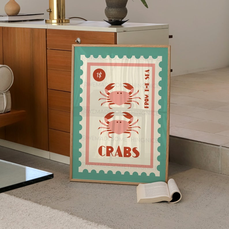 May include: A teal and pink framed poster with a vintage stamp design featuring two red crabs and the text "From the Sea, Crabs, 1$".