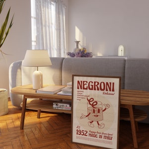 Peut inclure: Une affiche encadr&eacute;e rectangulaire pr&eacute;sentant le mot NEGRONI en grandes lettres rouges en haut. En dessous, un personnage en forme de verre de dessin anim&eacute; avec des bras et des jambes est centr&eacute;. Le texte inclut des ingr&eacute;dients, 1952 et MADE IN ITALY.