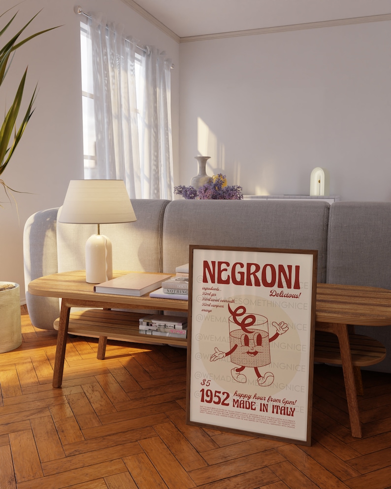 Peut inclure: Une affiche encadr&eacute;e rectangulaire pr&eacute;sentant le mot NEGRONI en grandes lettres rouges en haut. En dessous, un personnage en forme de verre de dessin anim&eacute; avec des bras et des jambes est centr&eacute;. Le texte inclut des ingr&eacute;dients, 1952 et MADE IN ITALY.