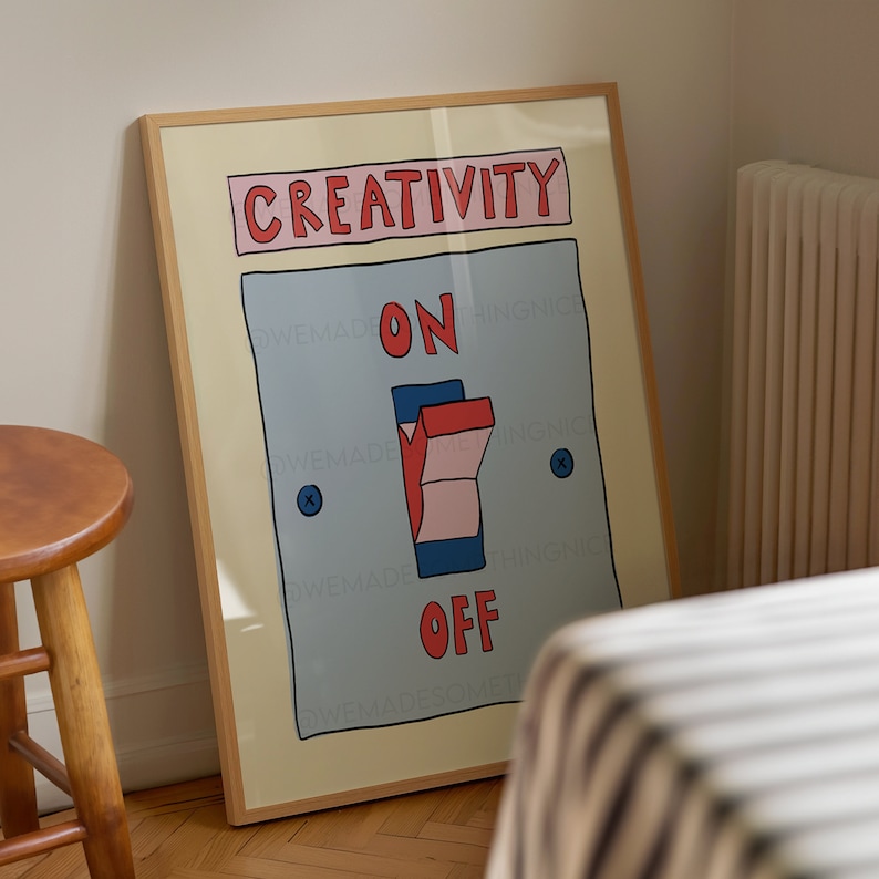 May include: A framed art print featuring a light blue switch with the words "CREATIVITY" above and "ON" and "OFF" below. The switch is in the "ON" position. The frame is a light wood color.