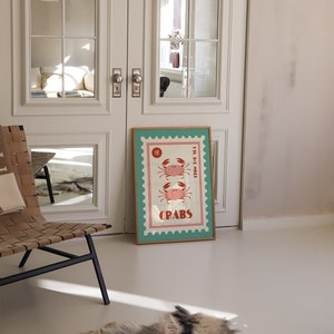 May include: A framed poster with a vintage design featuring two pink crabs on a blue and white background. The poster has a gold frame and the text "1&cent;" and "CRABS" is printed on it.