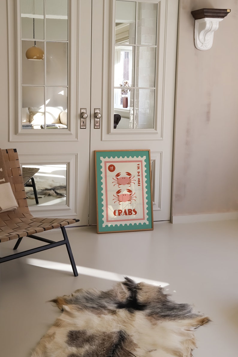 May include: A framed poster with a vintage design featuring two pink crabs on a blue and white background. The poster has a gold frame and the text "1&cent;" and "CRABS" is printed on it.