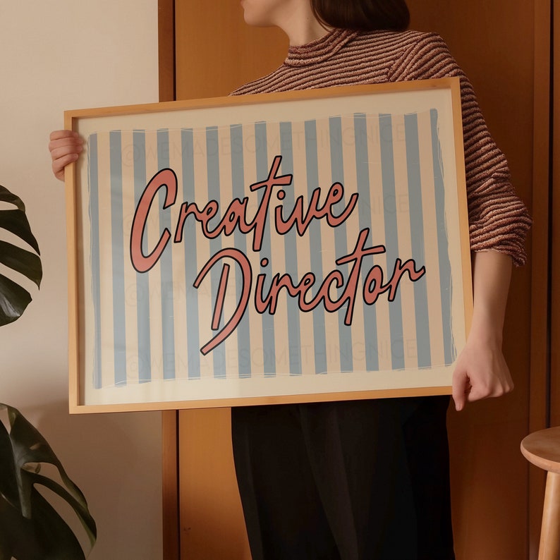 May include: A wooden framed print with blue and white stripes and the text "Creative Director" in pink lettering.