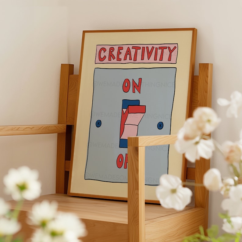 May include: A framed art print featuring a whimsical illustration of a light switch. The word "CREATIVITY" is above the switch, with "ON" and "OFF" on either side. The switch is in the "ON" position. The artwork is in a wooden frame.