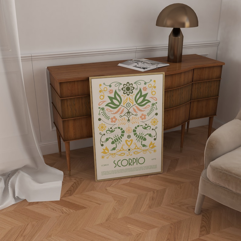 May include: A beige and gold framed print with a colorful illustration of the zodiac sign Scorpio. The illustration features green, yellow, orange, and pink flowers and two scorpions. The text "Scorpio" is written in a bold, black font.
