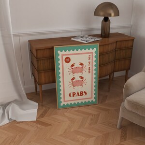 May include: A vintage-style poster with a teal border and a white background featuring two red crabs with the text "CRABS FROM THE SEA" and "1$" in the top left corner.