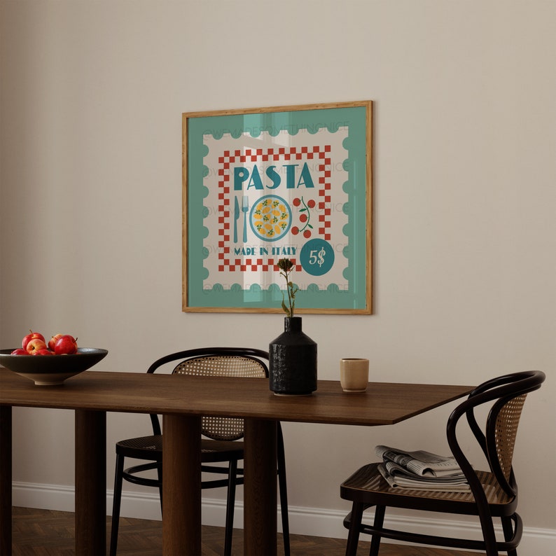 May include: A framed print with a retro pasta stamp design. The artwork displays the word "PASTA", a plate of food, and the text "MADE IN ITALY". The frame is wood-toned, and the background is a light teal colour.