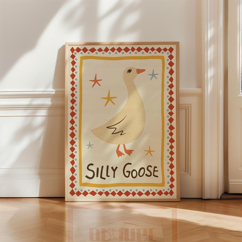 Puede incluir: Una impresi&oacute;n enmarcada con una ilustraci&oacute;n caprichosa de un ganso blanco con un pico rojo y patas naranjas. El ganso est&aacute; rodeado de estrellas amarillas y el texto "Silly Goose" est&aacute; impreso en marr&oacute;n.