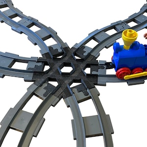 May include: A blue toy train with a yellow whistle and a figure of a worker in a white hard hat is on a gray plastic train track. The track is in the shape of a four-way intersection.