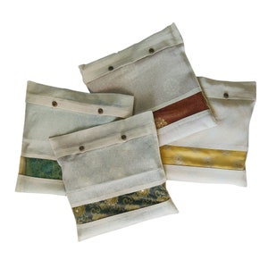 May include: Four white fabric storage bags with brown buttons. Each bag has a different patterned fabric lining, including green, gold, yellow, and red.