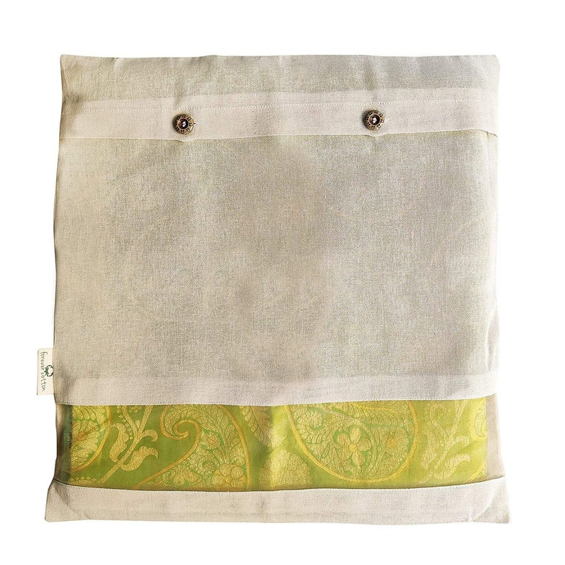 May include: A white cotton storage bag with two buttons and a green and gold patterned fabric lining. The bag is designed to store and protect delicate items like sarees.