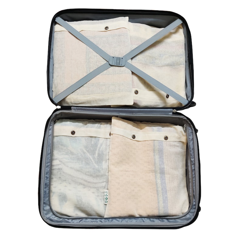 May include: Open black suitcase with four beige fabric packing cubes inside. The cubes have a drawstring closure and are labeled "GOOD".