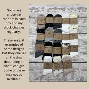 May include: A collection of assorted socks, each wrapped with a brown paper band. The socks feature various patterns, including hearts, polka dots, and stars. The text on the paper reads "Because just need hugs for you."
