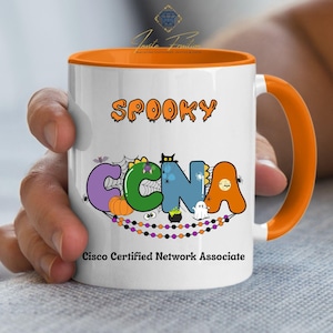 May include: White ceramic mug with an orange interior and handle. The mug features the word "SPOOKY" in orange lettering, and below, the letters "CCNA" are decorated with Halloween graphics. The text "Cisco Certified Network Associate" is printed at the bottom.