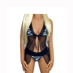 May include: Black sheer lingerie set with a lace trim. The top has a tie at the front and the bottom has a graphic print of the Seattle Seahawks logo.
