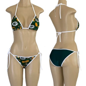 May include: Green and yellow bikini with a white trim. The top has a triangle shape and the bottom is a cheeky style. The bikini is printed with the Green Bay Packers logo and the word "Packers".
