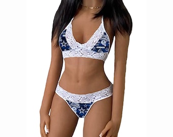 Puede incluir: Un conjunto de lencería de encaje blanco con un estampado azul y blanco con el logotipo y la estrella de los Dallas Cowboys. El conjunto incluye un top halter y un tanga.
