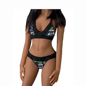 May include: Black lace lingerie set with a green and blue graphic print featuring the Seattle Seahawks logo and text. The set includes a bra and matching underwear.