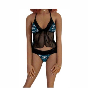 May include: Black and teal lingerie set with a lace trim. The set features a sheer top with a tie at the front and a thong bottom with a graphic print of a football team logo.