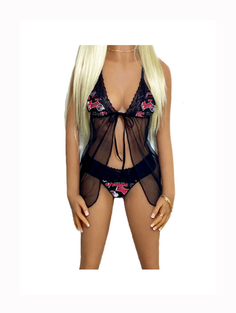 Puede incluir: Conjunto de lencer&iacute;a negra transparente con estampado gr&aacute;fico rojo y negro. La parte superior tiene un escote halter y un lazo en la cintura. La parte inferior es de estilo tanga con ribete de encaje.