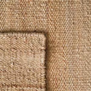 K&ouml;nnte beinhalten: Nahaufnahme eines Naturfaser-Teppichs mit gewebter Textur. Der Teppich ist hellbraun und hat eine leicht raue Oberfl&auml;che.