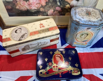 May include: Three vintage tin boxes with images of Queen Elizabeth II. The boxes are decorated with red, white, and blue colors and feature the royal crest and the text "Queen Elizabeth II Coronation 2nd June 1953".