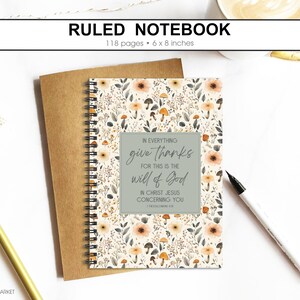 May include: Ruled notebook with a floral design, 6 x 8 inches, and 118 pages. The cover features a cream background with flowers and mushrooms. A gray square contains the text "In everything give thanks for this is the will of God".