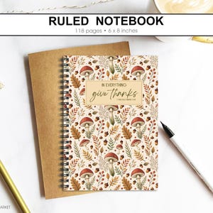 May include: Ruled notebook with a fall design of mushrooms, leaves, and acorns. The cover reads "In Everything Give Thanks" and measures 15 x 20 cm. The notebook has 118 pages.