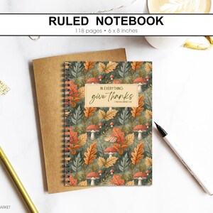 May include: Spiral-bound ruled notebook with a cover featuring autumn leaves and mushrooms. The notebook is 15 x 20 cm and has 118 pages. The cover includes the text "In everything give thanks."
