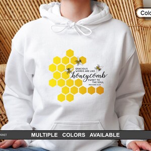 May include: White hoodie featuring a yellow honeycomb design with bees and the text "Gracious words are like honeycomb, sweet to the soul." Multiple colours are available. The hoodie has a drawstring hood.