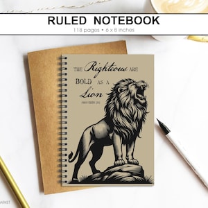 Puede incluir: Cuaderno rayado con encuadernación en espiral. La portada presenta una ilustración en blanco y negro de un león rugiendo y el texto "The Righteous are Bold as a Lion". El cuaderno mide 15 x 20 cm y tiene 118 páginas.