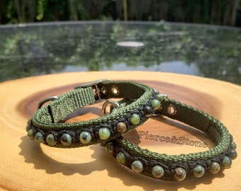 May include: Two green dog collars with green and black beads. The collars are on a wooden surface. The larger collar has the text "Pierce & Stone" on it.