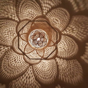 May include: A close-up of a decorative light fixture with a geometric pattern. The light fixture is made of wood and has a warm, inviting glow.