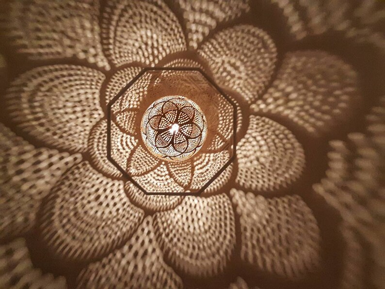 May include: A close-up of a decorative light fixture with a geometric pattern. The light fixture is made of wood and has a warm, inviting glow.