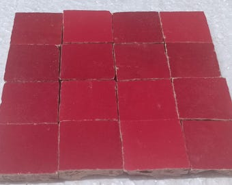 May include: A set of 16 red square ceramic tiles. The tiles are arranged in a grid pattern.