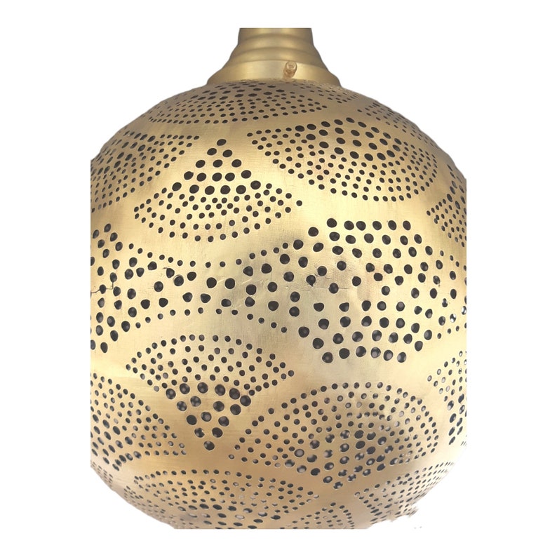 May include: A gold metal pendant light fixture with a round, perforated shade. The shade has a pattern of small circles and larger, curved shapes.