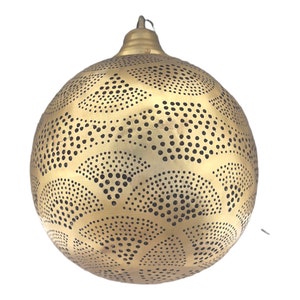 May include: A gold metal pendant light fixture with a round, spherical shape. The fixture has a decorative pattern of small circles and curved lines.