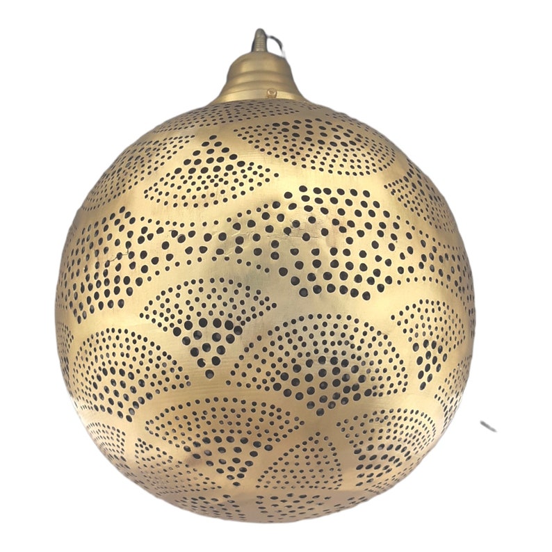 May include: A gold metal pendant light fixture with a round, spherical shape. The fixture has a decorative pattern of small circles and curved lines.