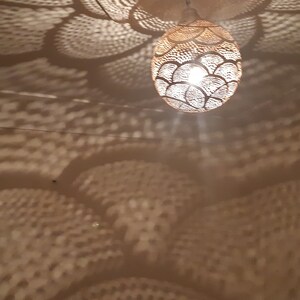 May include: A white ceiling with a round, woven, light fixture hanging from it. The light fixture casts a pattern of overlapping circles on the ceiling.