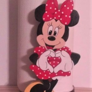 May include: A red and white Minnie Mouse paper towel holder. Minnie is wearing a red dress with white polka dots and is making a heart shape with her hands.