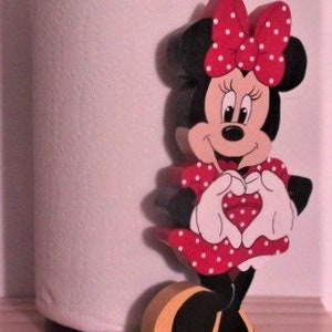 May include: A red and white wooden paper towel holder featuring a cartoon character of Minnie Mouse making a heart shape with her hands.