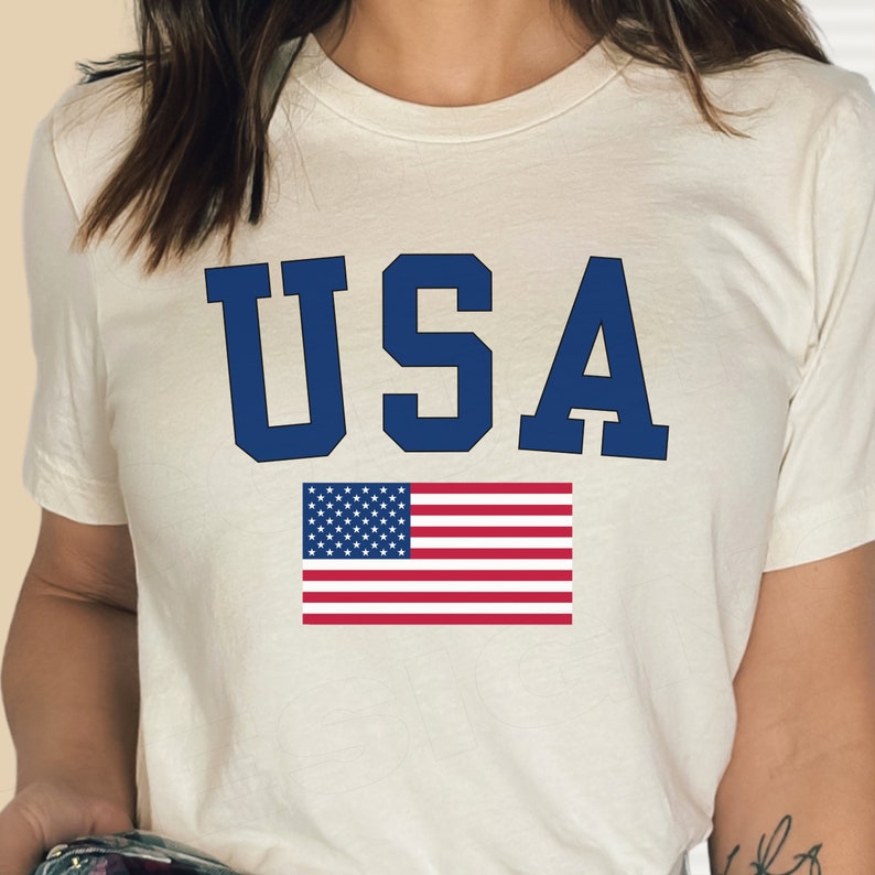 May include: White t-shirt with a blue "USA" graphic and a small American flag.